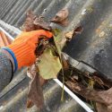 Man cleaning out gutters in the fall