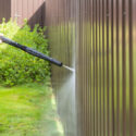 Cleaning fence with high pressure power washer, cleaning dirty wall.